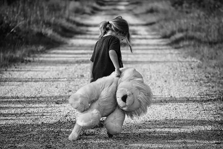Niña pequeña arrastrando un oso de peluche por un camino, imagen en blanco y negro representando las heridas de la infancia