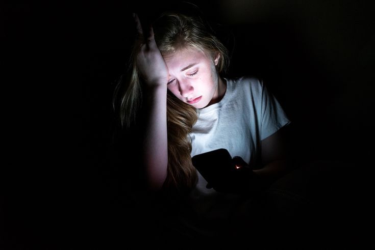 Adolescente mirando el móvil con expresión preocupada, ilustrando el impacto de las redes sociales en la salud mental de los jóvenes